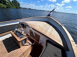 1978 Sloop 785 boat with wooden deck, steering wheel, and flag on a sunny day.