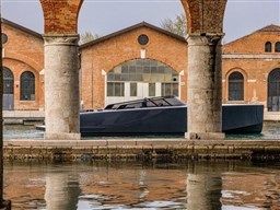 2025 VanDutch 56 yacht docked near historic brick buildings and stone pillars.