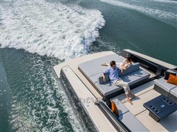 2025 VanDutch 56 yacht cruising with passengers relaxing on deck, leaving a wake in the water.