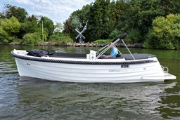 Corsiva 690 Tender boat from 2012 on a serene lake with lush greenery.