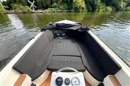 Corsiva 690 Tender 2012 boat interior with black seating, on a calm river near lush greenery.