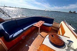 Luxurious 2008 INTER 9000 Sportivo boat interior with blue seating and wooden deck on a sunny day.