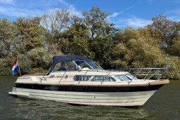 2008 INTER 9000 Sportivo boat cruising on a river with lush greenery backdrop.