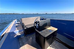 Isloep Rapida 990 boat interior with steering wheel, wooden deck, and seating, on a sunny day.