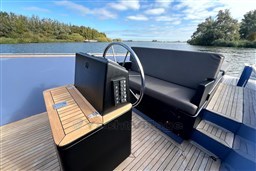 Isloep Rapida 990 boat interior, featuring steering wheel and seating, on a scenic waterway.