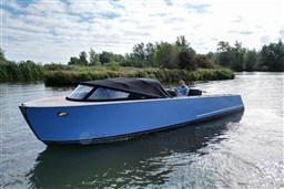 Blue Isloep Rapida 990 boat cruising on a calm river, surrounded by lush greenery.