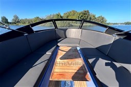 Isloep Rapida 990 boat interior with wooden table, gray seating, and scenic water view.