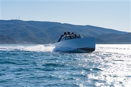 2025 VanDutch 75 yacht cruising on open water with mountainous backdrop.