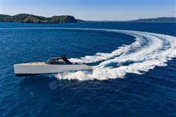 2025 VanDutch 75 yacht cruising swiftly on open blue sea with scenic island backdrop.