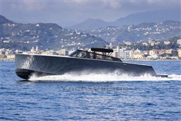 2025 VanDutch 48 yacht cruising on blue waters with scenic coastal backdrop.