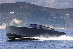 2025 VanDutch 48 yacht cruising on the water with scenic mountain backdrop.