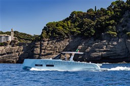 2026 Pardo Yachts 43 cruising near rocky coastline with lush greenery.