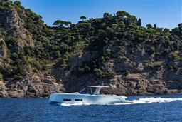 2026 Pardo Yachts 43 cruising near rocky coastline with lush greenery.