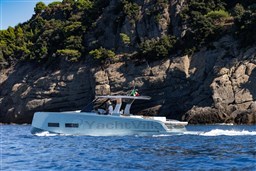 2026 Pardo Yachts 43 cruising near rocky coastline with lush greenery.