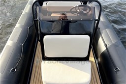 2021 Infanta 750 boat interior with steering wheel and cushioned seating on water.