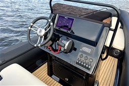 Cockpit of 2021 Infanta 750 boat with steering wheel and control panel on water.