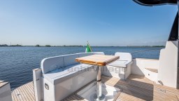 2024 Apreamare GOZZO 38 CABIN yacht deck with seating and table, overlooking serene water.