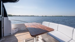 2024 Apreamare GOZZO 38 CABIN yacht deck with seating and table, overlooking serene water.