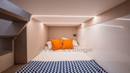 2024 Apreamare GOZZO 38 CABIN interior with cozy bed, orange pillows, and modern lighting.