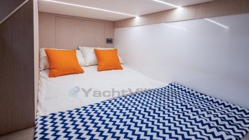2024 Apreamare GOZZO 38 CABIN interior with cozy bed, orange pillows, and zigzag blanket.