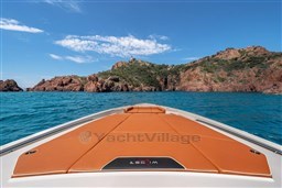 2024 Wider Wilder 60 yacht cruising near rocky coastline under clear blue sky.