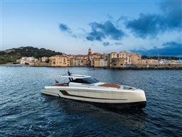 2024 Wider Wilder 60 yacht cruising near a coastal town at sunset.