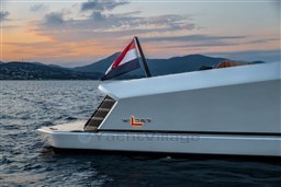 2024 Wider Wilder 60 yacht at sunset on the water, featuring sleek design and flag.