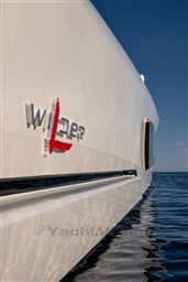 2024 Wider Wilder 60 yacht on calm sea, showcasing sleek design and logo.
