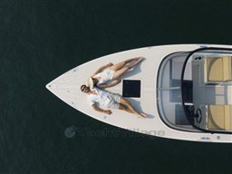 Couple relaxing on 2025 VanDutch 32 yacht, aerial view, serene water backdrop.