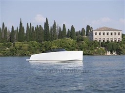 2025 VanDutch 32 yacht on serene water with lush greenery and historic building backdrop.