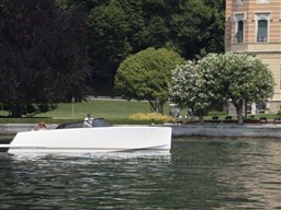 2025 VanDutch 32 yacht cruising on a serene lake near a historic building.