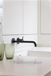 Modern minimalist bathroom sink with sleek black faucet and green glass decor.
