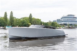 2024 VanDutch 40 yacht on a calm river with modern buildings in the background.