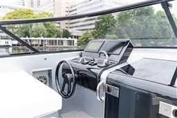 2024 VanDutch 40 yacht helm with sleek controls and modern design, set against an urban backdrop.
