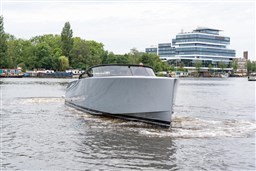 2024 VanDutch 40 yacht cruising on a river with modern buildings in the background.