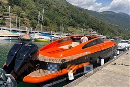 Orange and black Albatro EVO 45 boat docked at a marina, surrounded by scenic hills.
